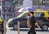 A women takes the protection of an umbrella to beat the heat at Shivaji Park 