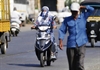 A women with her face covered drives a scooter under the hot sun at Badlapur